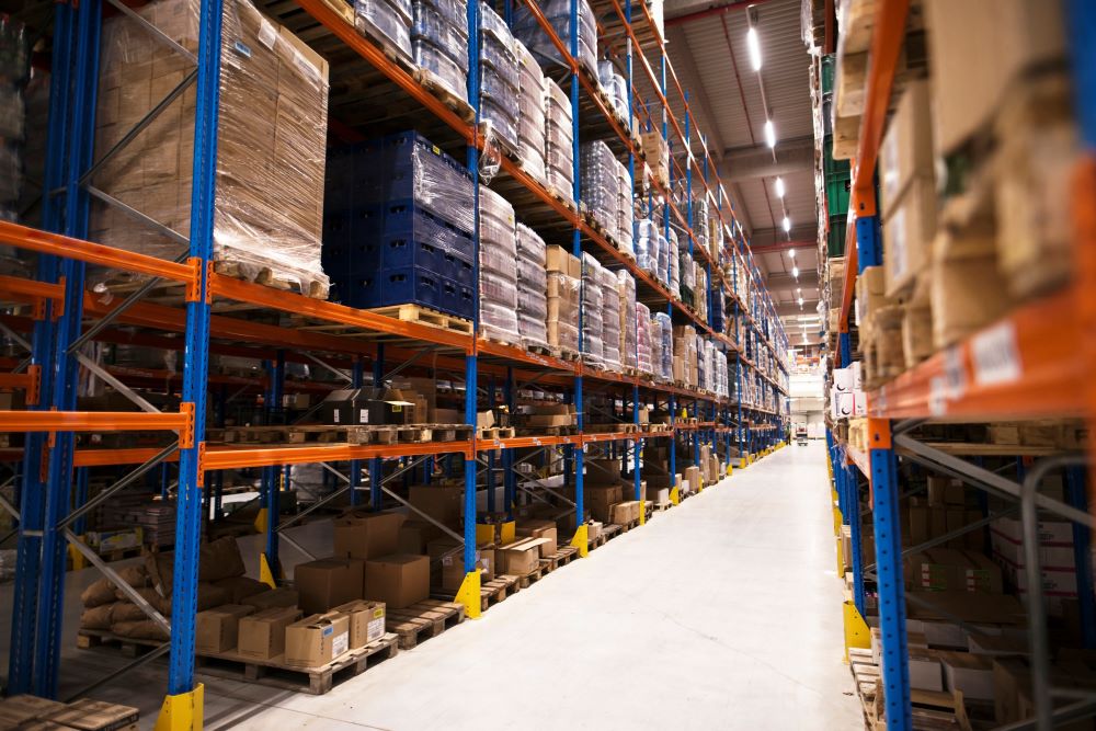 Interior large distribution warehouse with shelves stacked with palettes goods ready for market.